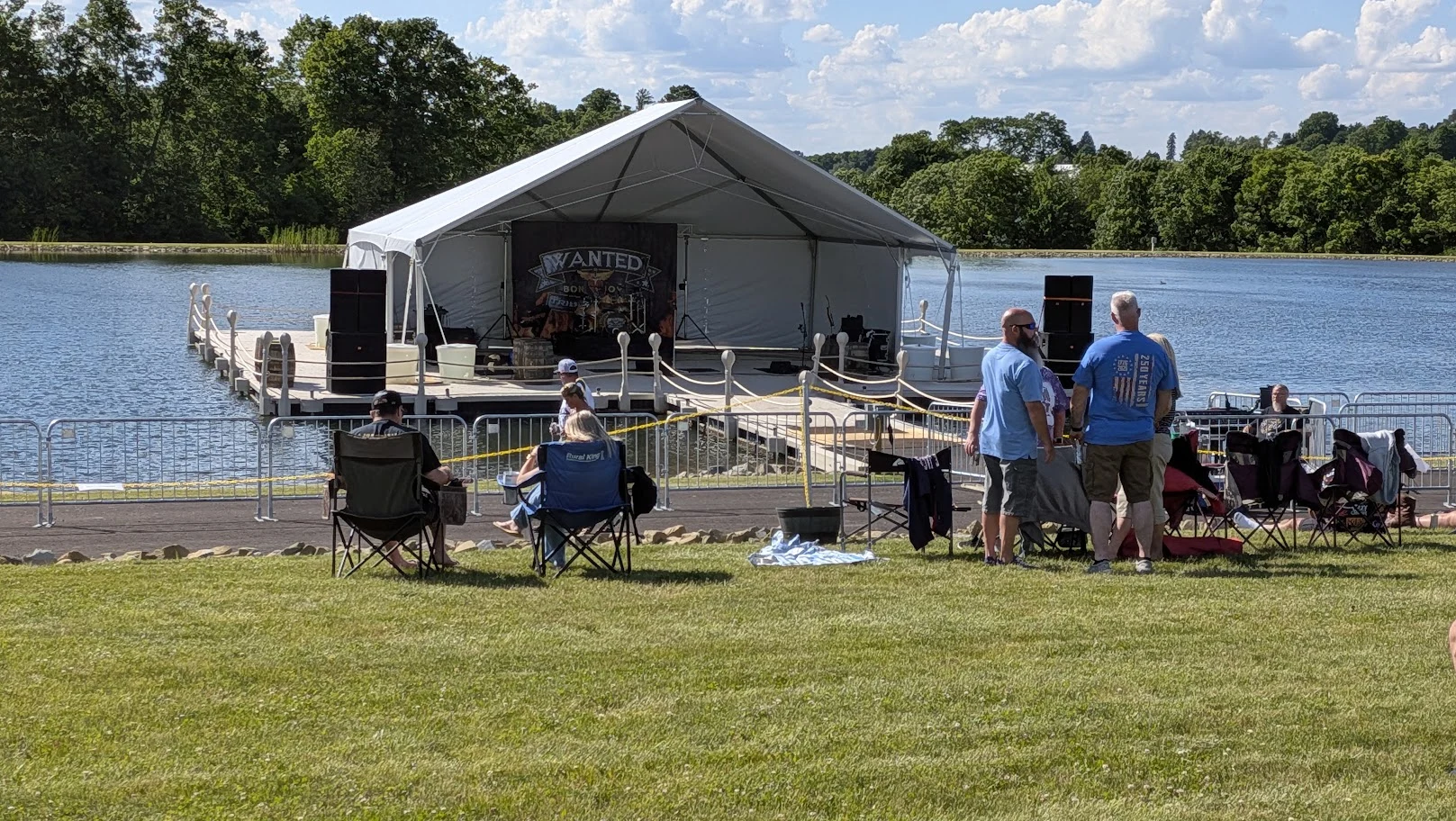 The waterfront platform set up for live music, with spectators gathering on the lawn.