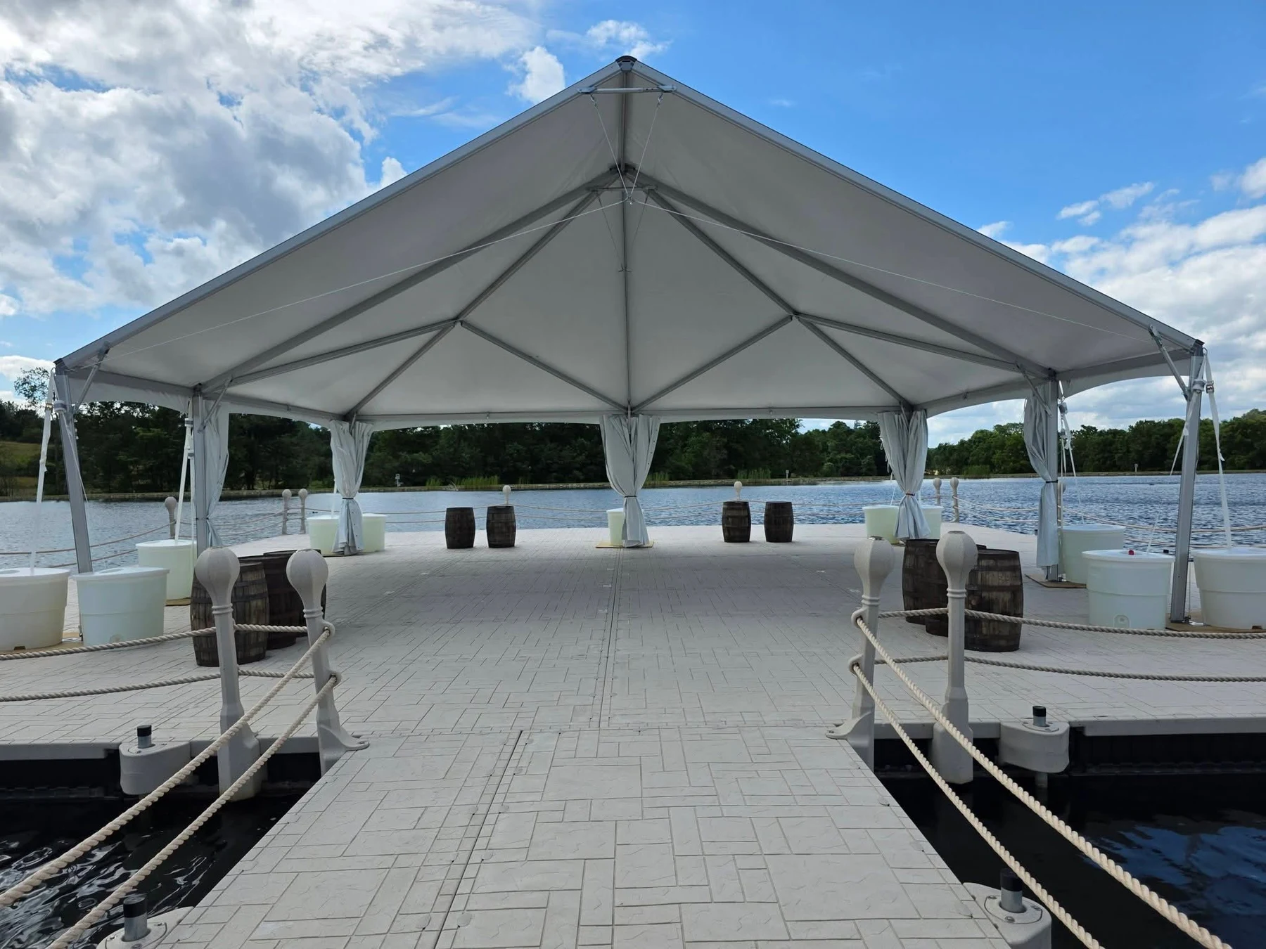 The rope-lined dock approach and floating event platform beneath the white tent at the floating event pavilion.