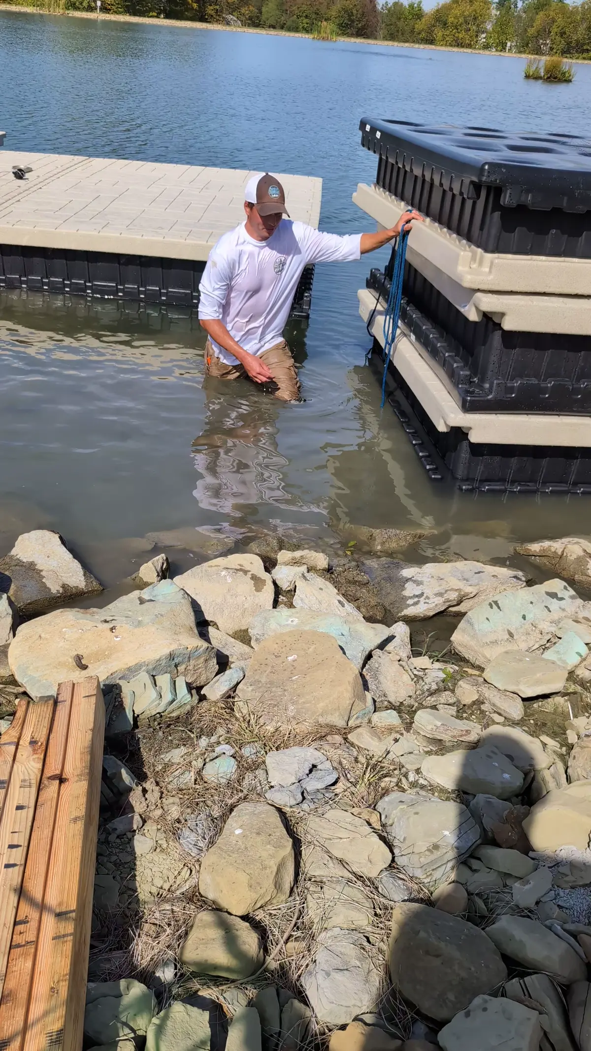 Video still showing dock sections stacked beside the shoreline during installation.