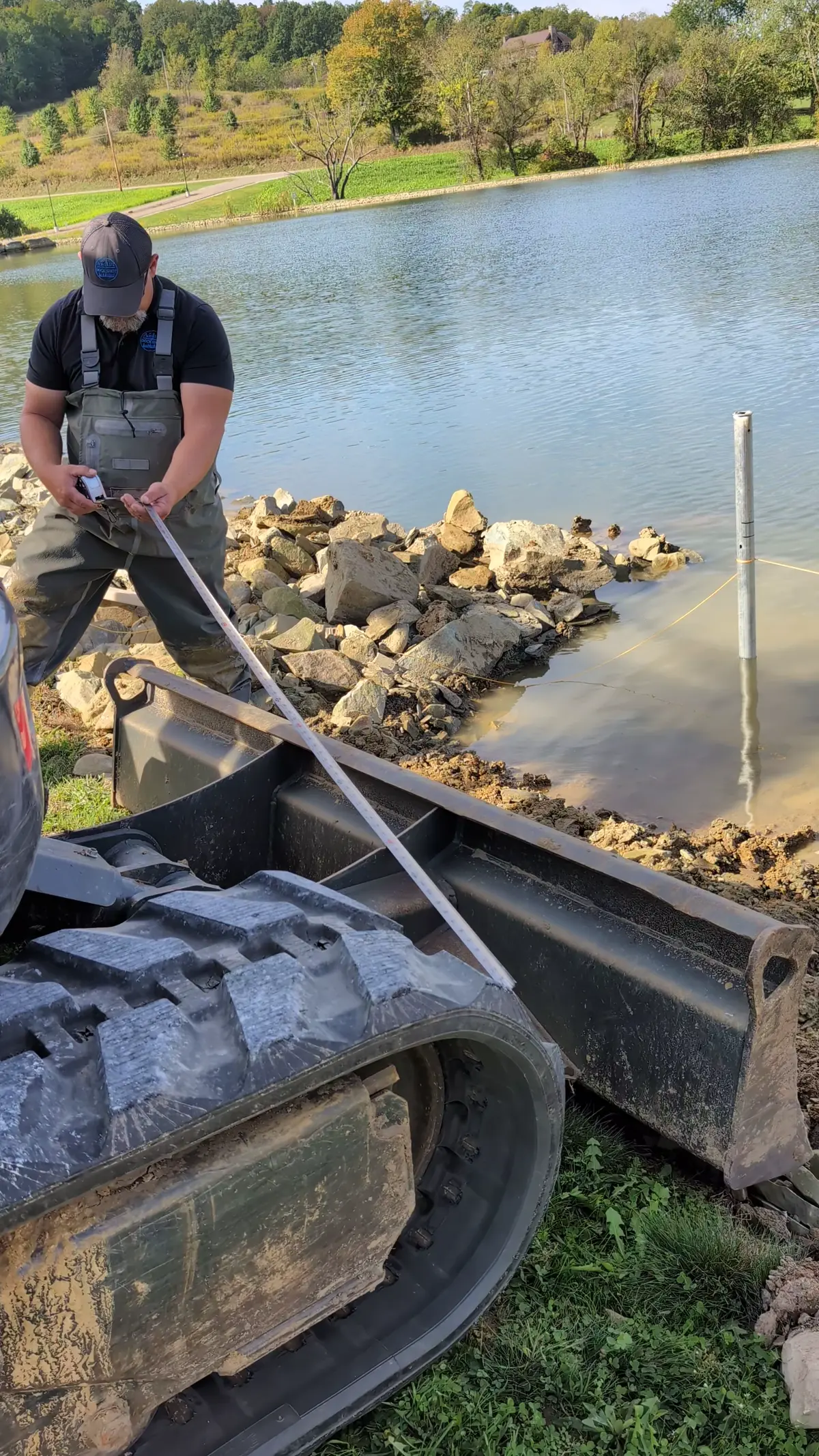 A crew member working beside equipment and stone at the Big Prairie shoreline