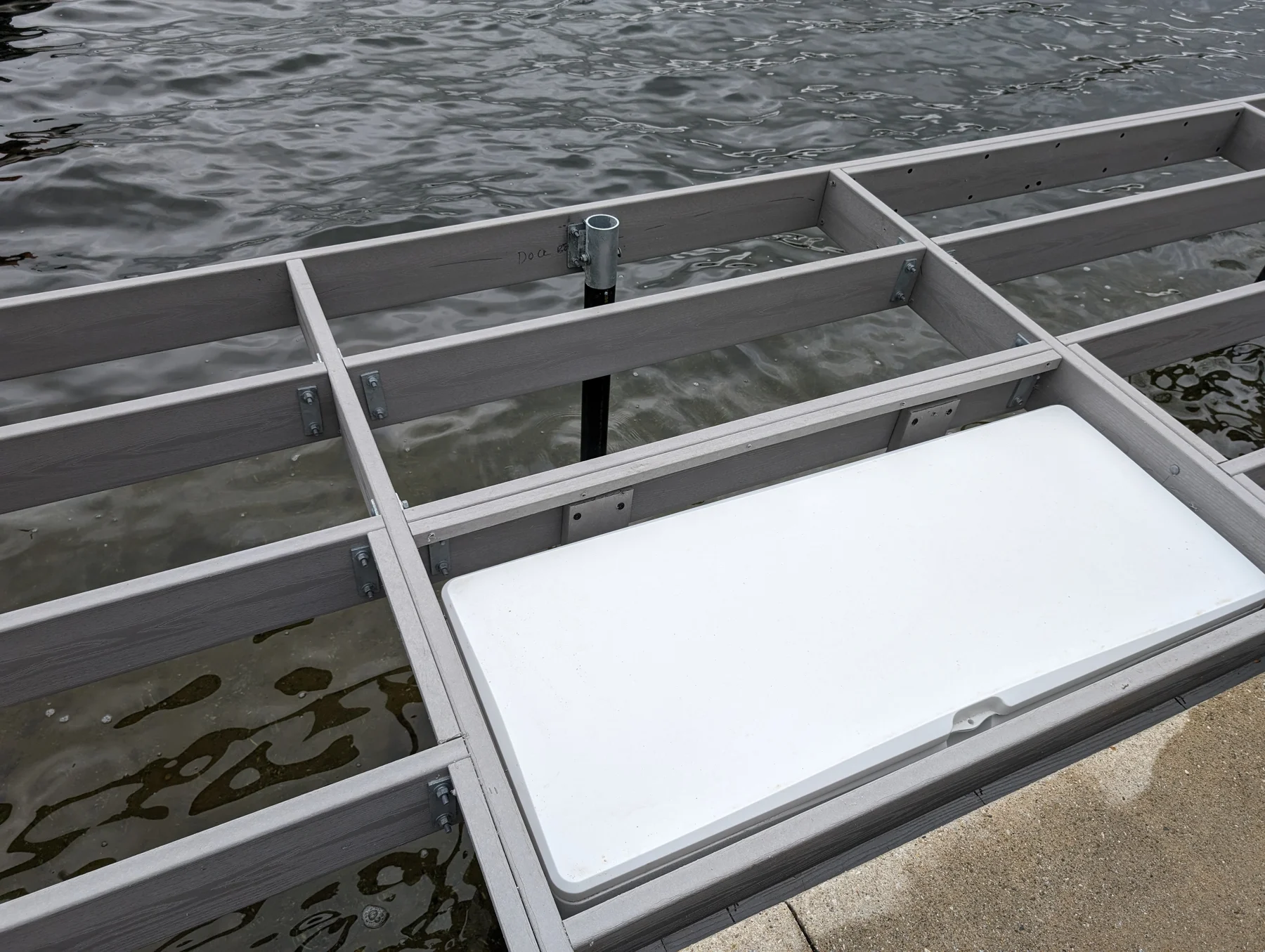 Close view of a white storage box and lid set within the dock framing.