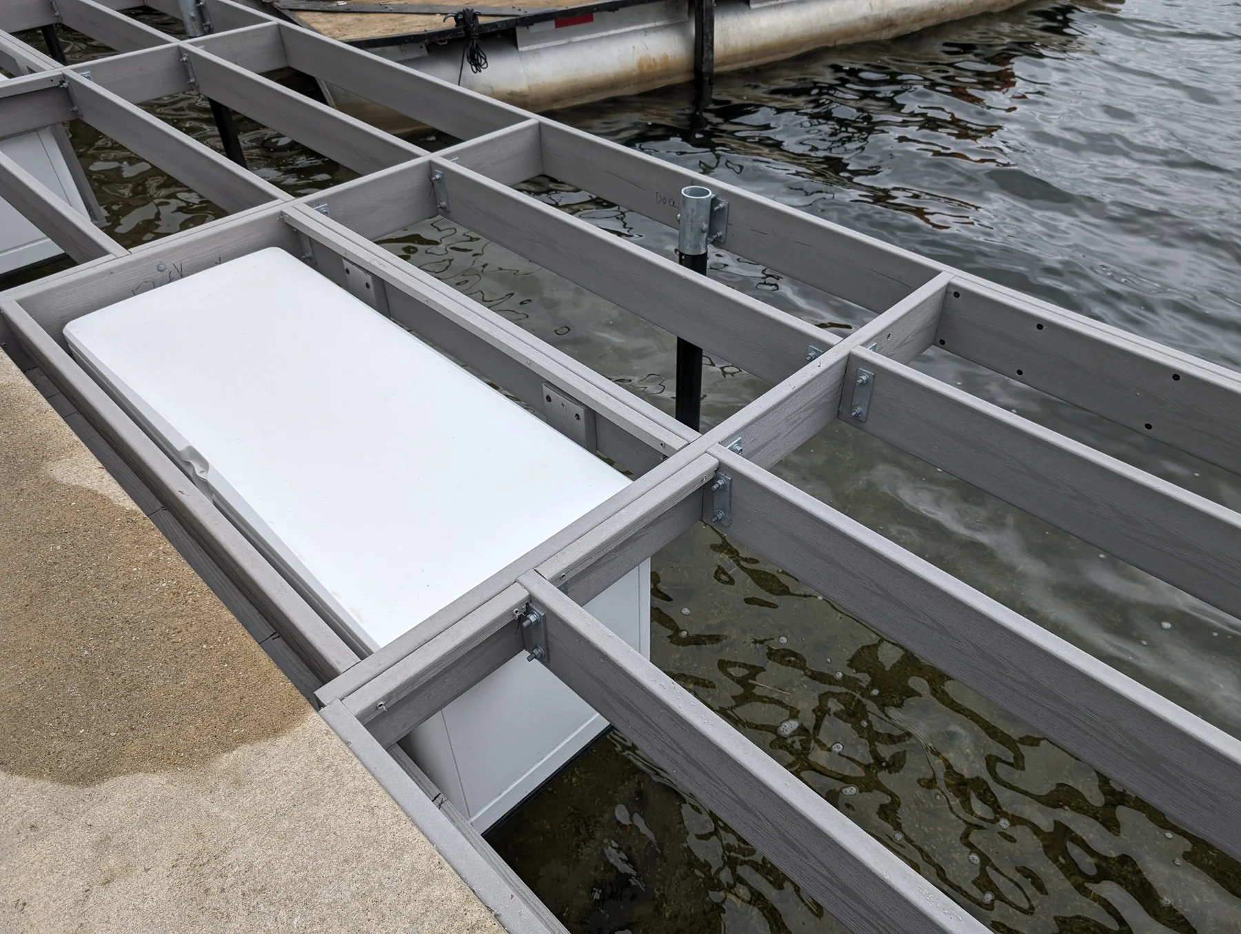 A white dock storage box fitted between the structural members during construction.
