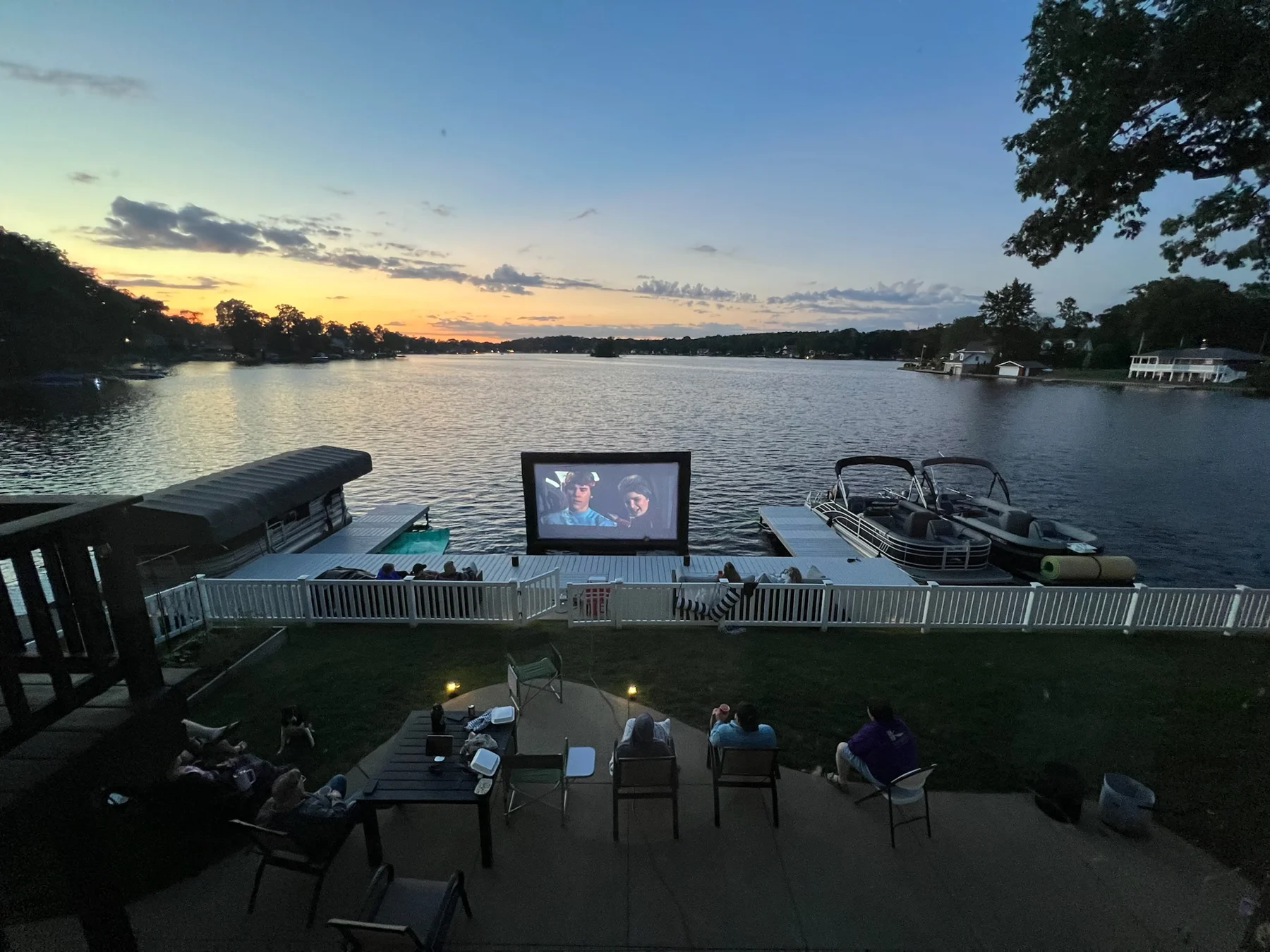 The waterfront in use at sunset, with an outdoor movie screen and seating near the dock.