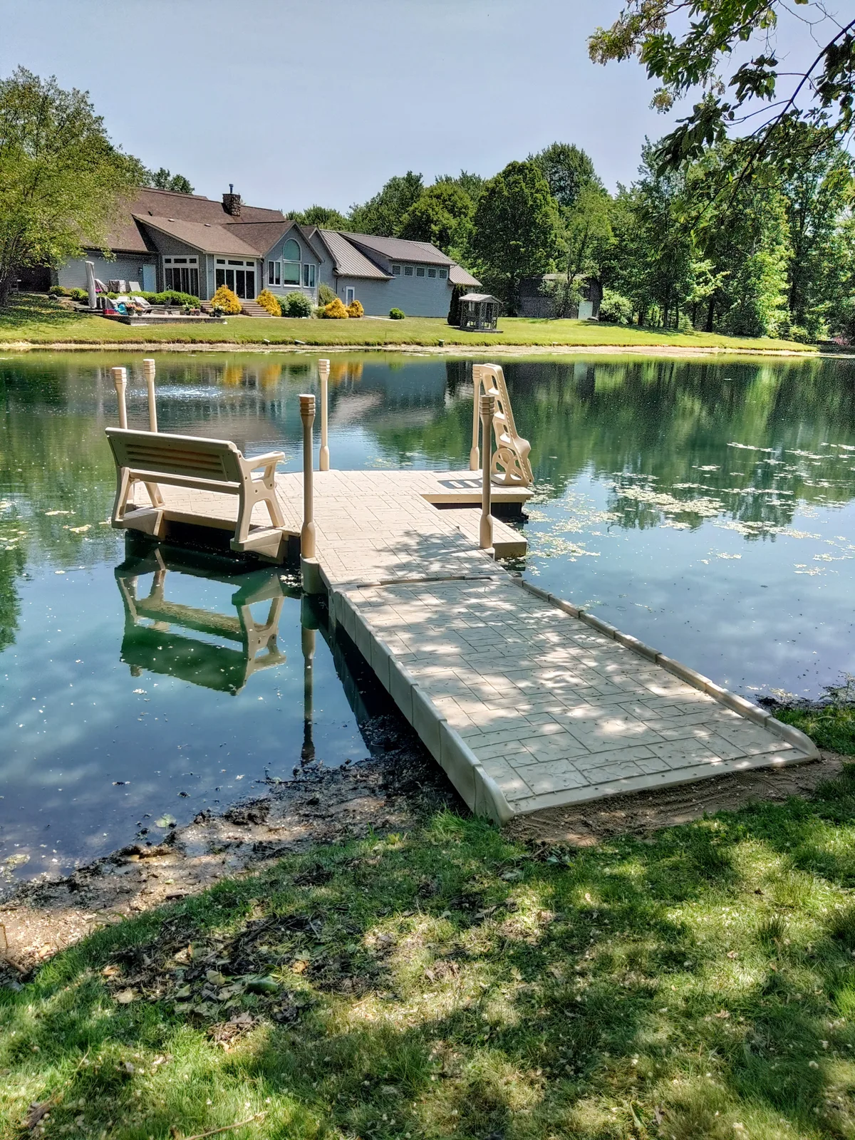Bench and swim ladder on a floating dock overlooking a landscaped private pond