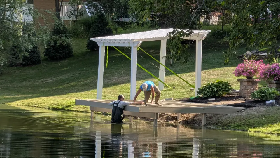 AquaLife crew assembling a dock frame at the shoreline