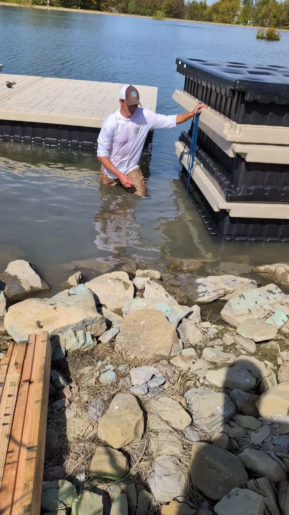 Video still showing dock sections stacked beside the shoreline during installation.