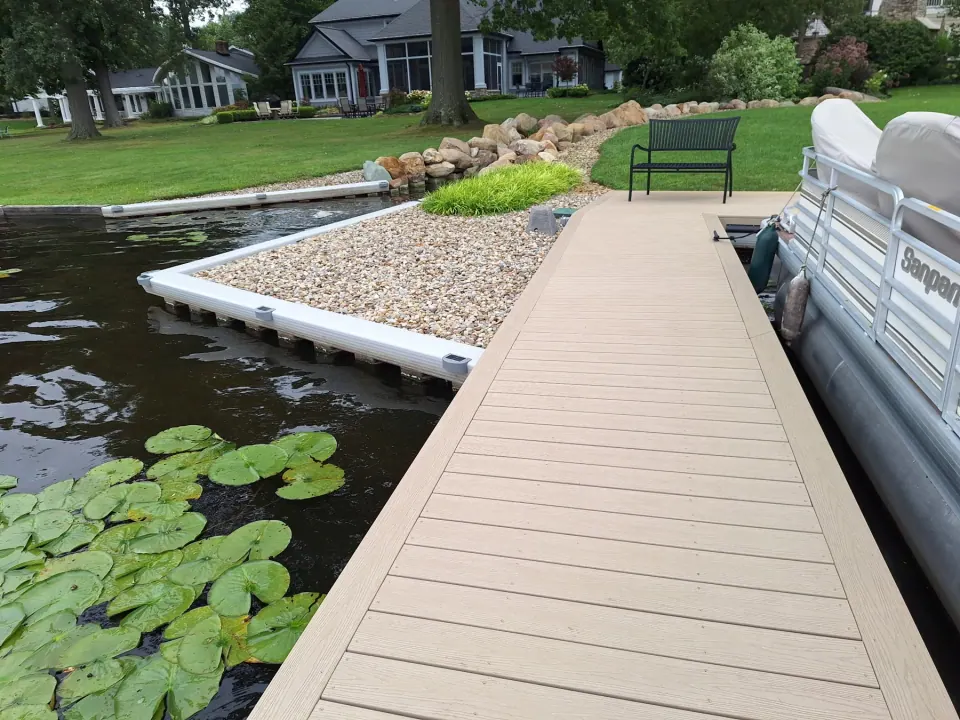 Seawall cap, stone border, and dock walkway with a bench and lily pads