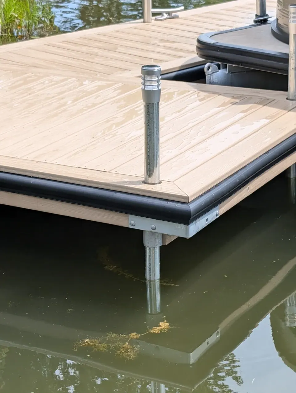 Corner hardware, pipe support and black bumper beneath the WearDeck surface.