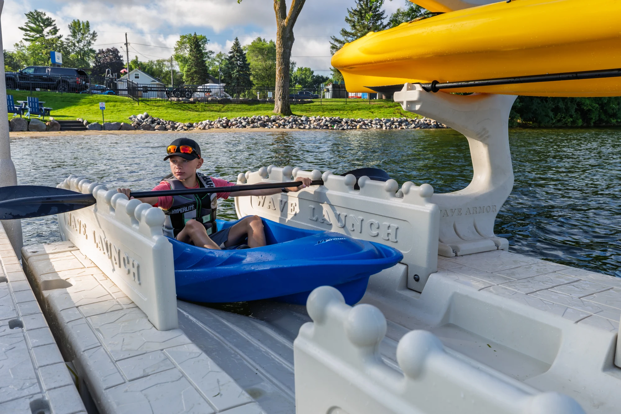 A paddler wearing a life jacket seated in a kayak between the launch hand-grip rails.