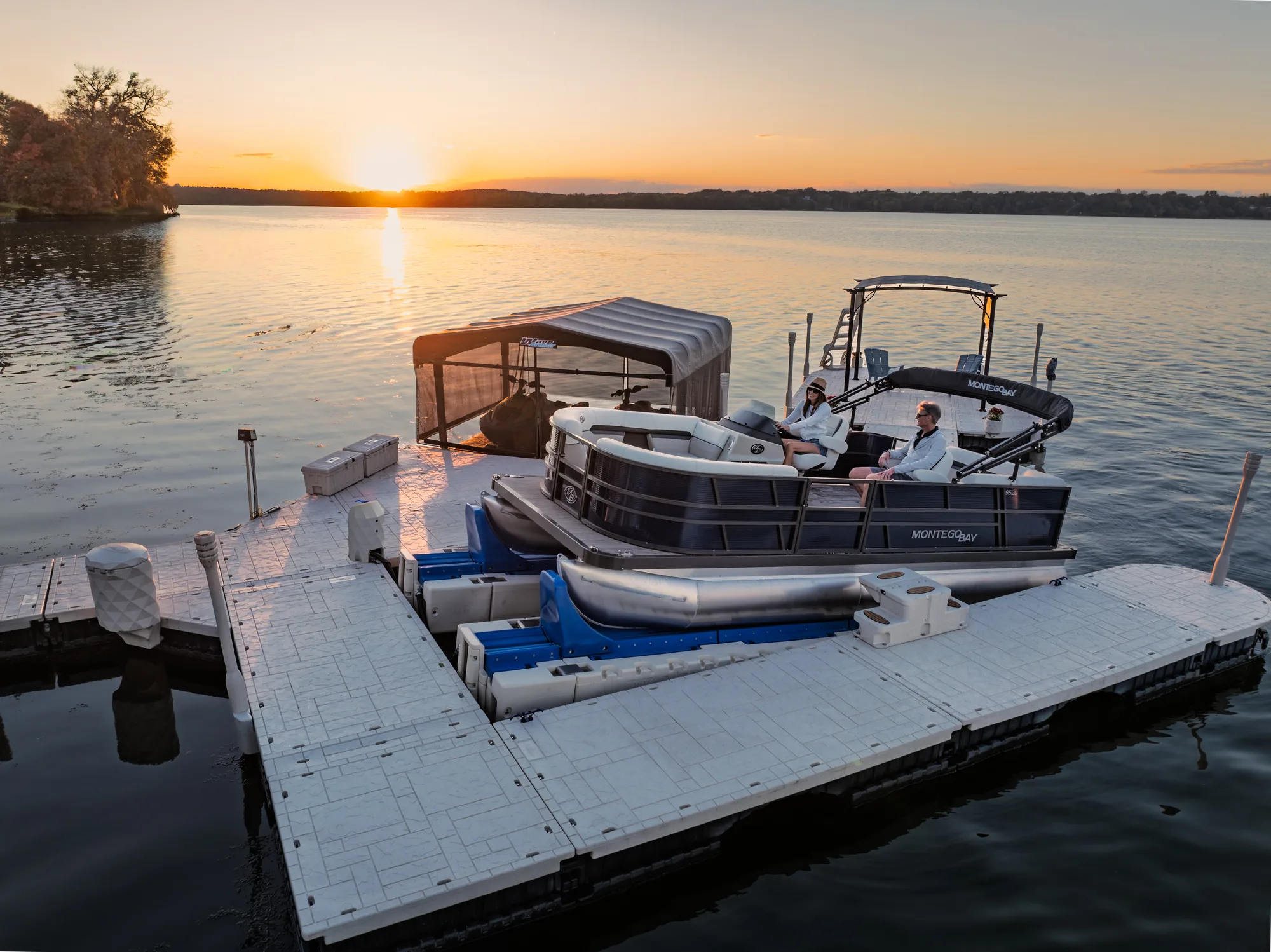 People relaxing on a pontoon supported by a Wave Armor Pro Air lift beside a floating dock at sunset